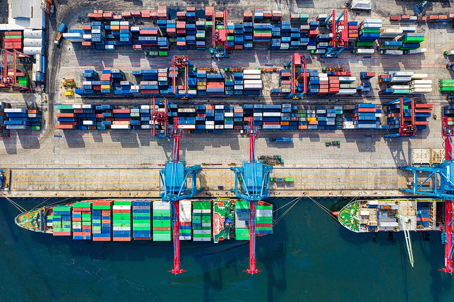 Aerial view of a large cargo ship being loaded with shipping containers.