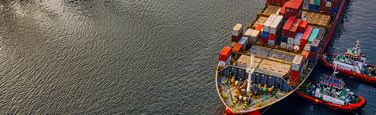 Cargo vessel and tug boats by a harbour pier