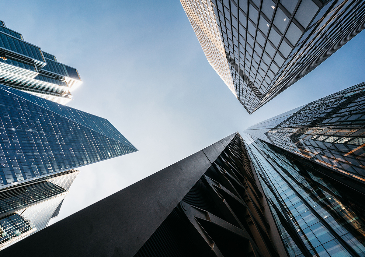 Extreme low-angle view of glass and steel skyscrapers towering directly overhead.